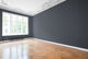 An empty room, big window, wooden floor and freshly painted dark grey walls.