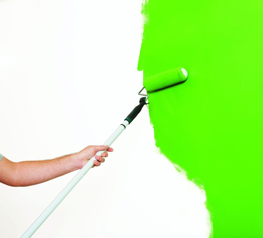 Rota roller with extension pole being used to paint a wall.